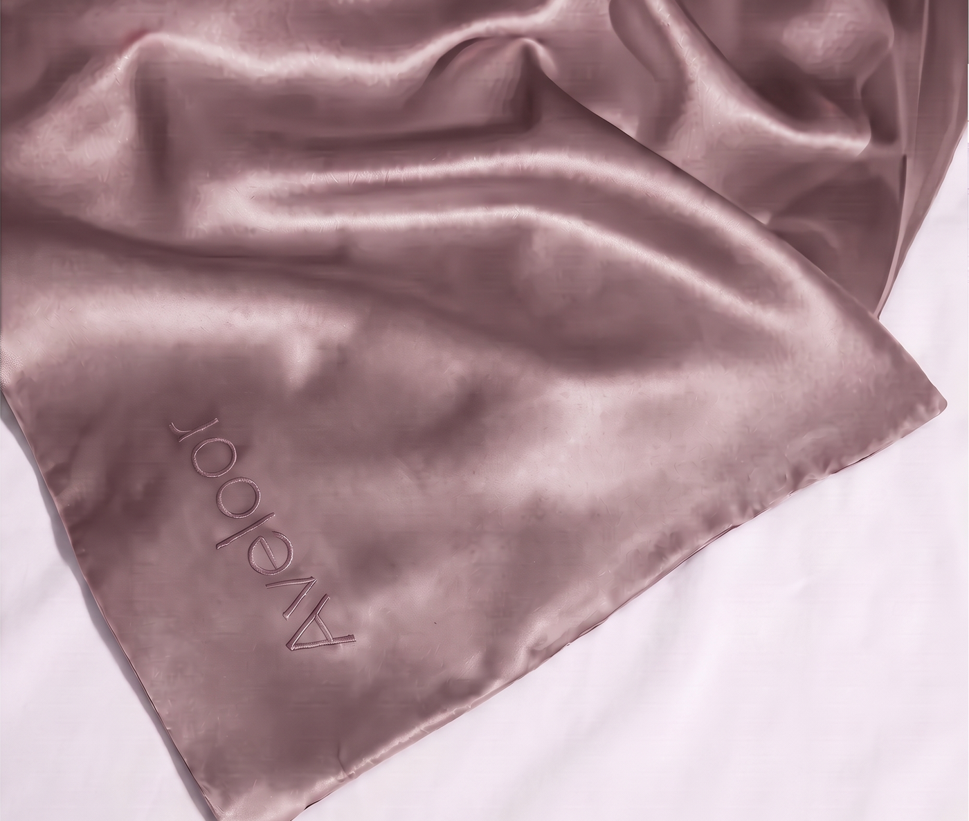 Aveloor mulberry silk pillowcase draped over the corner of a bed